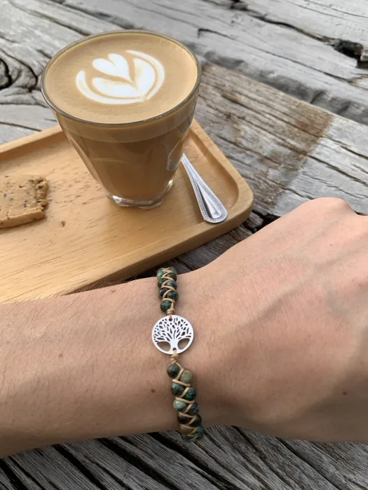 Bracelet argent porté au poignet devant un café latte